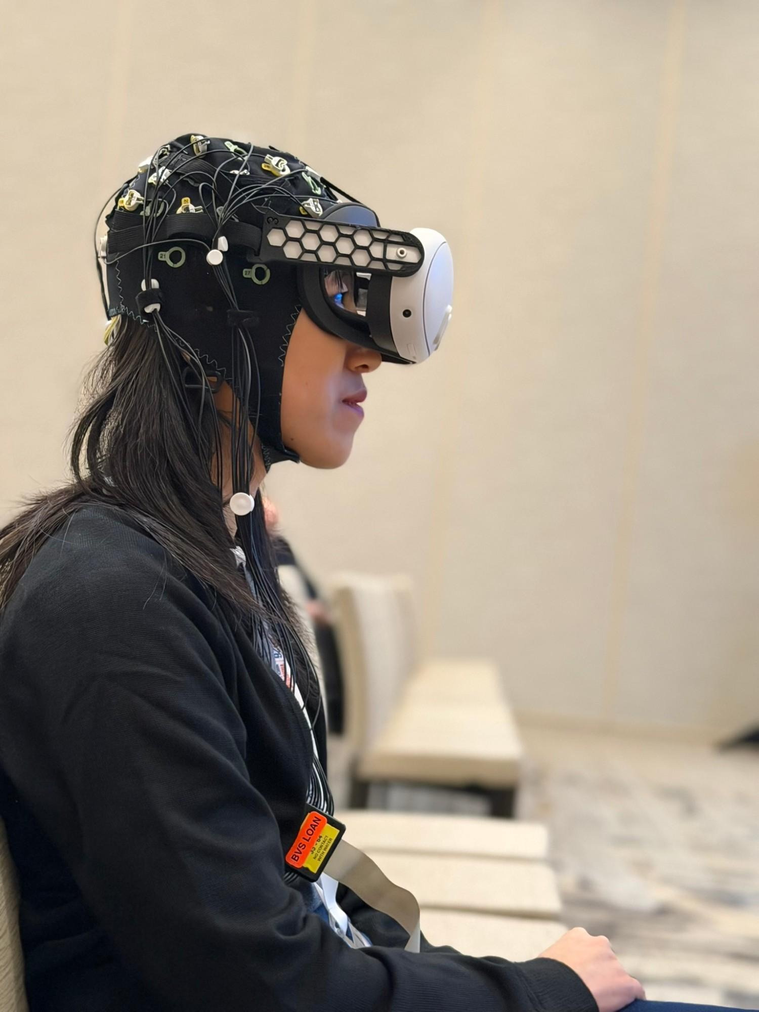 A seated person wearing an EEG cap and a VR headset