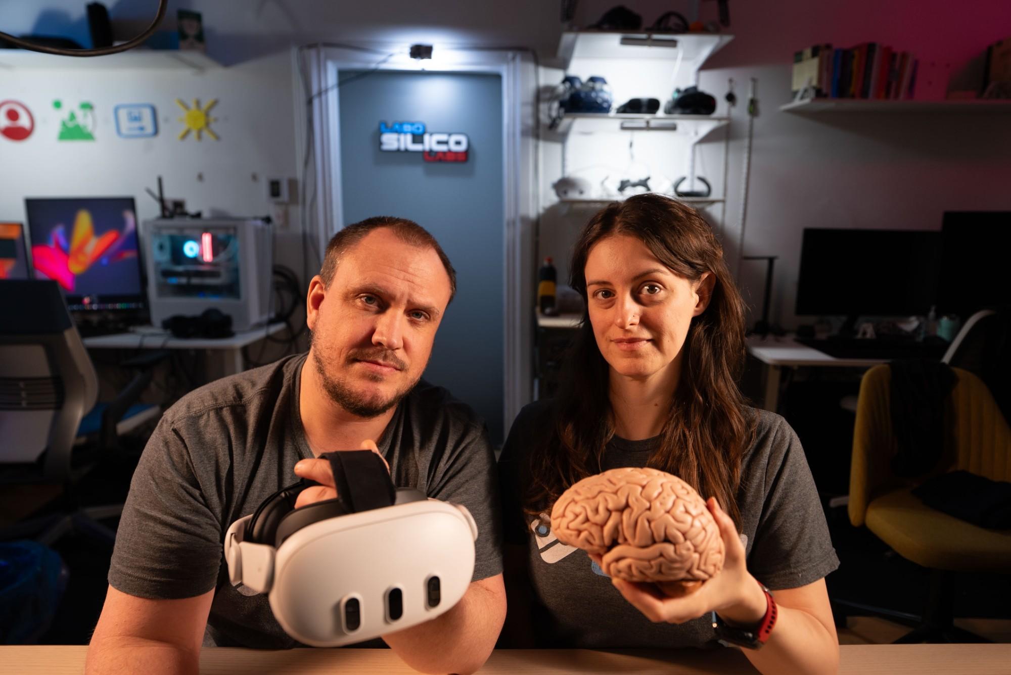 Two researchers, one holding a VR headset and the other a model of the human brain